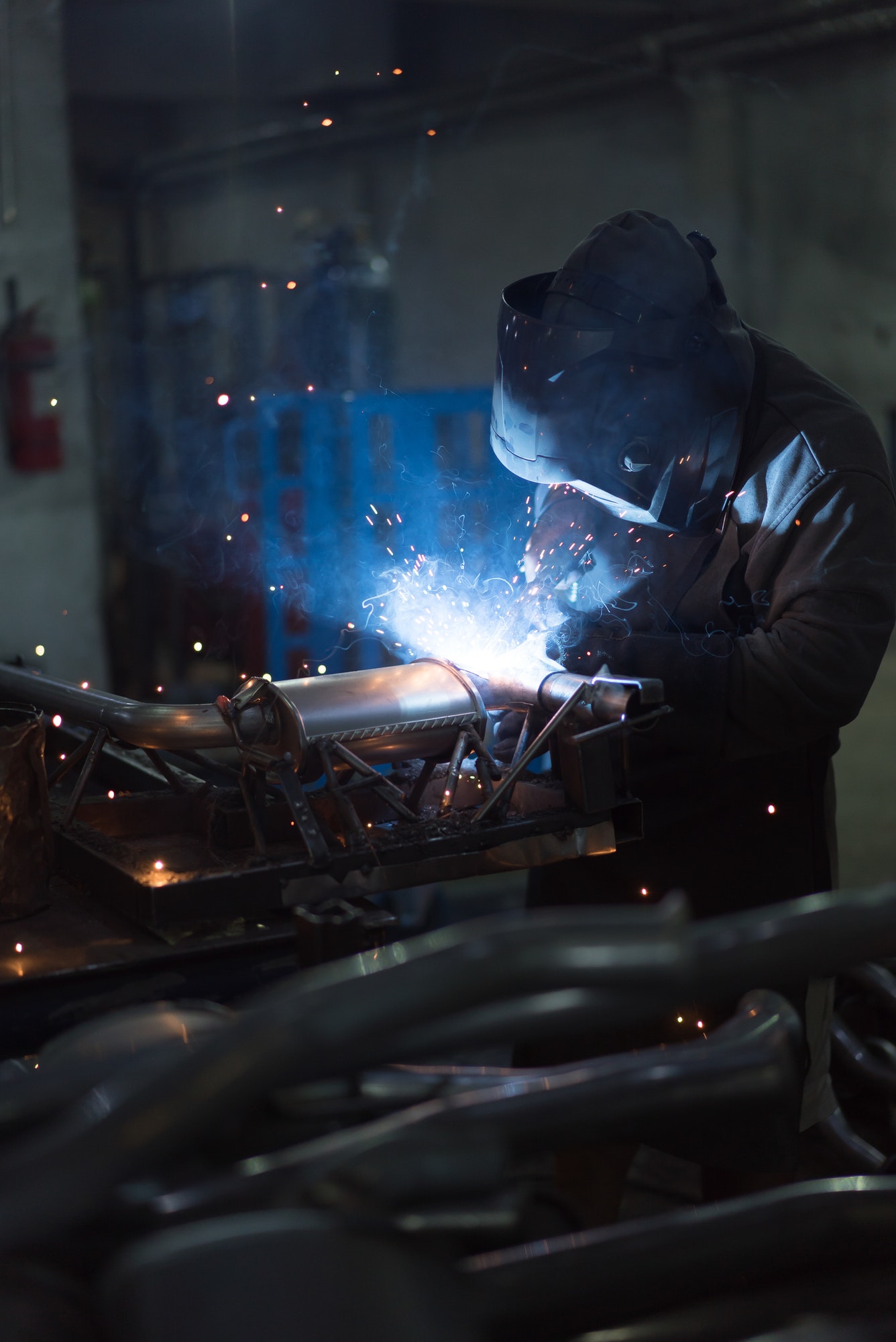 worker welding exhaust pipes pieces together